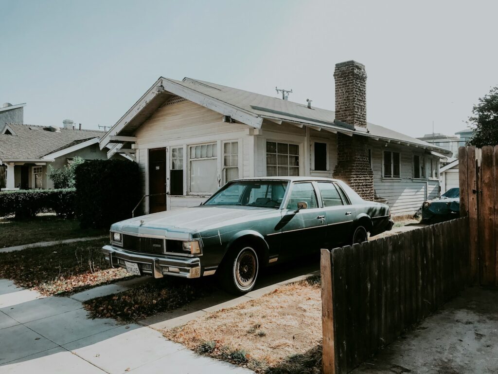 black sedan parked beside brown wooden fence