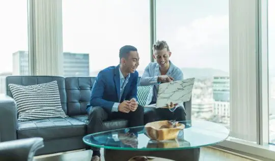 two men in suit sitting on sofa