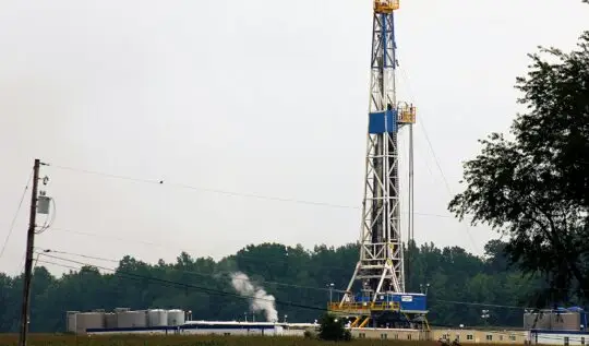 a large tower with smoke coming out of it with Marcellus Formation in the background