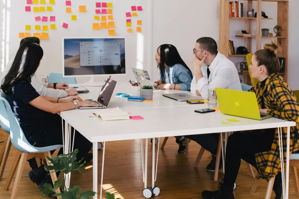 five person by table watching turned on white iMac | Maximizing Profit from Selling Land in Texas | Landowner Strategies for Developers